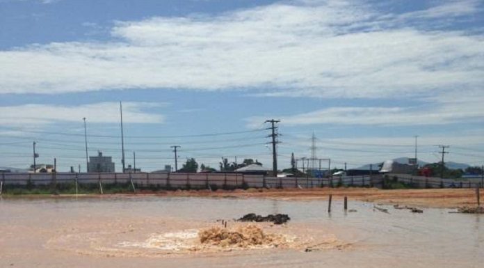 grade lago barrento formado em área aberta de onde sai do meio uma fonte de água, adutora rompida no solo