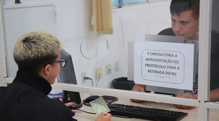 Emissão da carteira de identidade: cidadão conversa com atendente em uma cabine através de um vidro