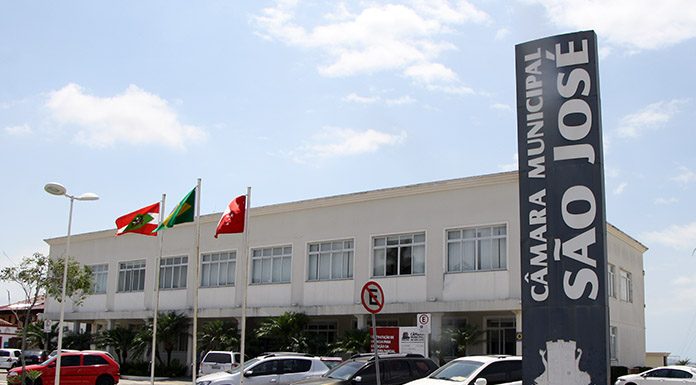 foto externa do prédio camara de vereadores de são Joosé com um placa vertical na frente e carros estacionados