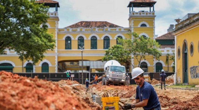 operário dentro de vala aberta no lar da alfândega com caminhão de concreto ao fundo e o mercado público