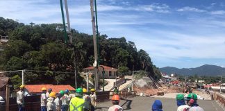 trabalhadores com capacetes em cima da estrutura de ferro de elevado para ser concretada