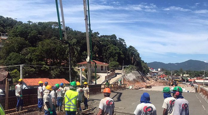 trabalhadores com capacetes em cima da estrutura de ferro de elevado para ser concretada