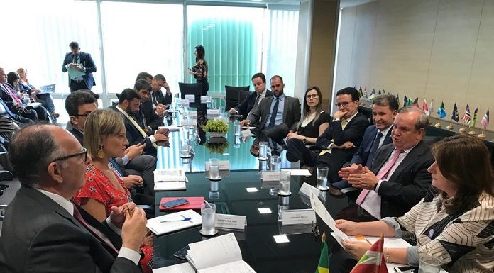 diversas pessoas reunidas e conversando em volta de uma grande mesa preta