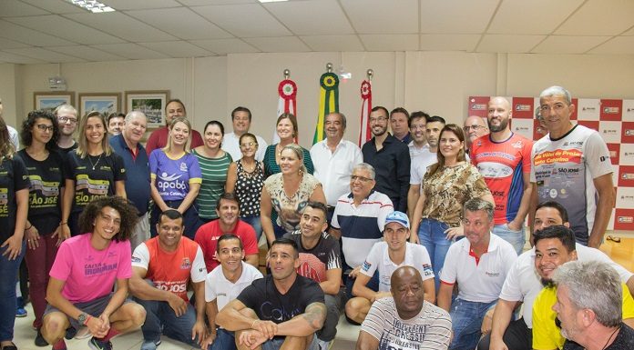 adeliana e o vice prefeito posam com grande grupo de atletas (homens e mulheres) no gabinete da prefeitura