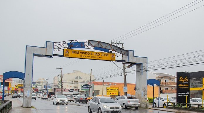 pórtico da avenida leoberto leal com placas de trânsito e carros passando em baixo em dia de chuva