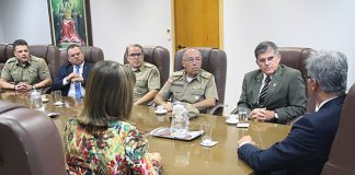 integrantes da pm e do tjsc conversam em uma mesa com o secretario nacional, que está de costas na ponta