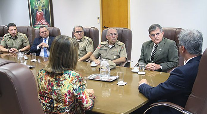 integrantes da pm e do tjsc conversam em uma mesa com o secretario nacional, que está de costas na ponta