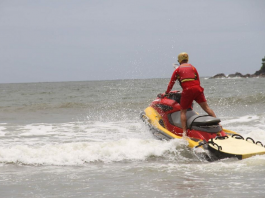 guarda-vidas em jet ski passando por ondas em uma praia