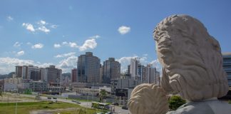 foto na altura da cabeça da estátua com a cidade de fundo