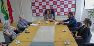 grande mesa onde estão reunidos, prefeita, delegado geral, delegada, vereador e secretária conversando