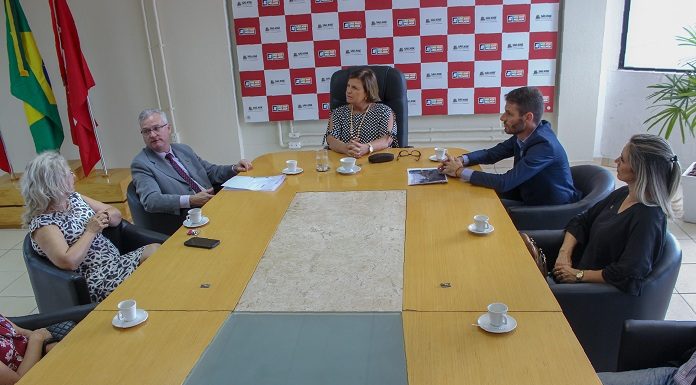 grande mesa onde estão reunidos, prefeita, delegado geral, delegada, vereador e secretária conversando