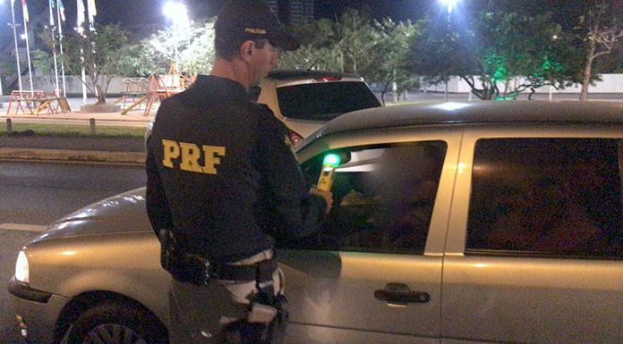 Policial rodoviário fazendo o teste de bafômetro em motorista