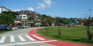 pista de corrida sem ninguém no parque de coqueiros e construções ao fundo