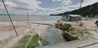 riacho na praia com quadra de areia ao lado e casebre de madeira