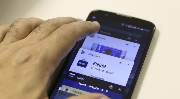 mão sobre um smartphone com logo do enem na tela