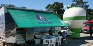 trailer da casan estacionado com toldo aberto com logo da companhia, balão inflável e mesas com cadeiras à frente