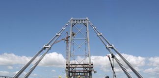 foto do chão gradeado da ponte, da torre e de das barras de olhas que sustentam a estrutura dos lados