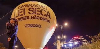 balão inflável da operação lei seca em via pública com uma agente da guarda ao lado e viatura na cabeceira da ponte