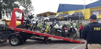 motos em cima de um guincho com um agente da prf ao lado olhando