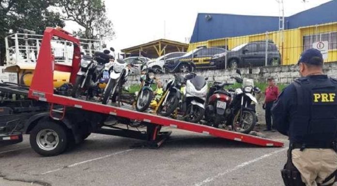 motos em cima de um guincho com um agente da prf ao lado olhando