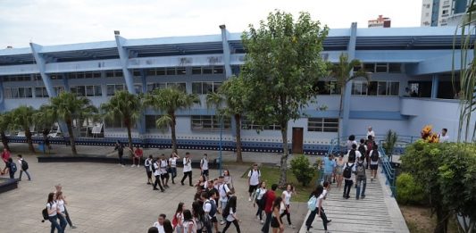 foto do prédio e do pátio do instituto estadual de educação com alunos em uma fila