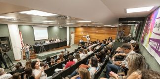 auditório da alesc lotado e com pessoas em bancada em palco à frente