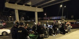 agentes da prf ao lado de diversas motos com pessoas em volta de noite