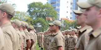 soldados da pmsc vistos de lado em pé alinhados em um gramado