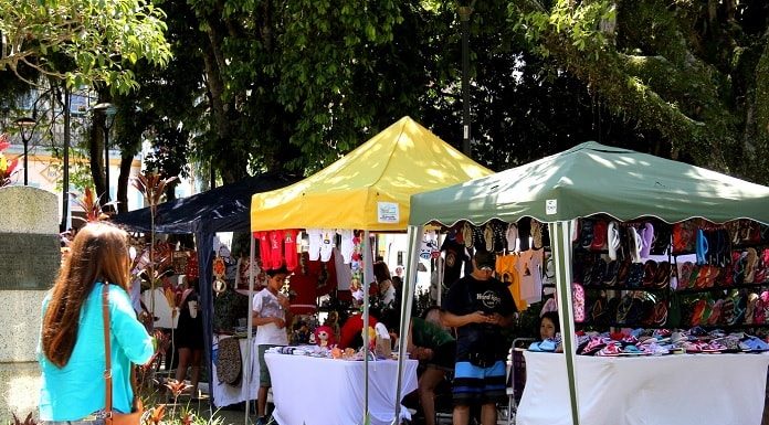 barracas de feira na praça e mulher passando entre os canteiros