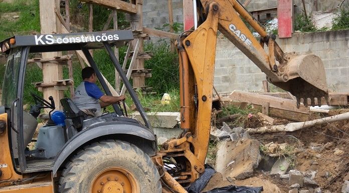 retroescavadeira com o braço demolindo uma construção em andamento