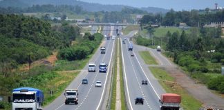 trecho da rodovia que se estende ao fundo da imagem com carros passando nos dois sentidos