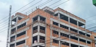 prédio em construção com placa na frente escrita "aemflo nova sede"