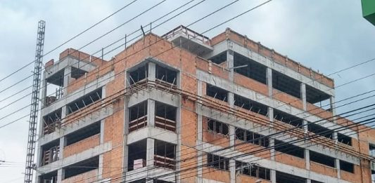 prédio em construção com placa na frente escrita "aemflo nova sede"