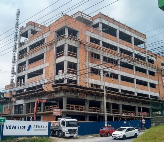 prédio em construção com placa na frente escrita "aemflo nova sede"