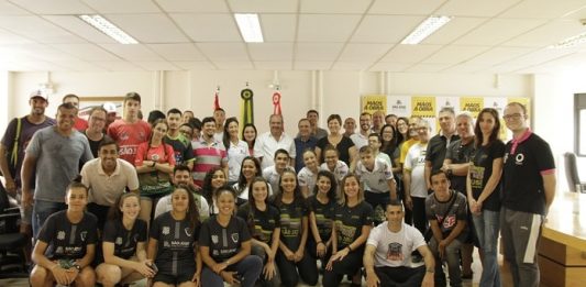 dezenas de pessoas, a maioria atletas, posando para a foto com a prefeita e vice no meio