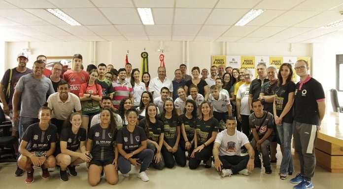 dezenas de pessoas, a maioria atletas, posando para a foto com a prefeita e vice no meio