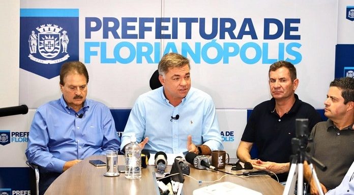 gean dando entrevista ao lado de secretário com painel ao fundo da prefeitura