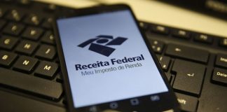 celular com logo da receita federal ocupando toda tela sobre teclado de computador