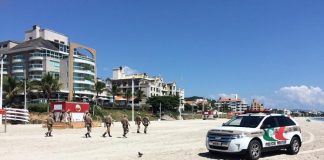 carro ford edge da pm na faixa de areia de canasvieiras com cinco policiais andando e prédios ao fundo