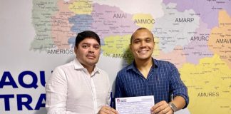 clonny capistrano e manoel galeno posam para a foto segurando juntos a ficha de filiação; há um mapa de sc na parede