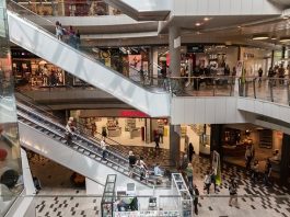 área central de um shopping com pessoas em escadas rolantes