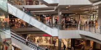 área central de um shopping com pessoas em escadas rolantes