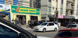 caminhonete da defesa civil e carro do procon municipal estacionados em avenida com comércios do outro lado da rua