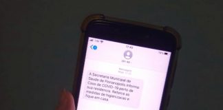 close em tela de celular com mensagem de alerta de proximidade de caso de coronavírus