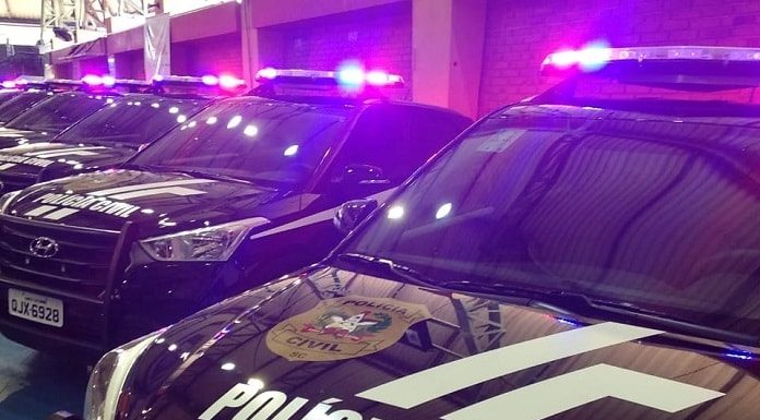 viaturas suv da polícia civil em galpão com sinais luminosos ligados