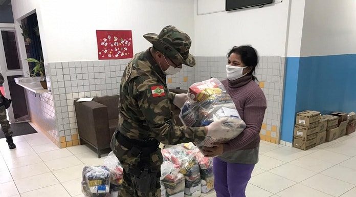 Policial militar entregando alimentos a uma senhora