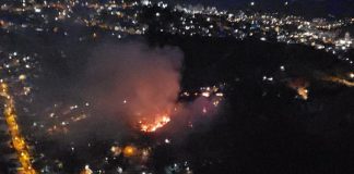 foto aérea em área escura com foco de incêndio no meio e luzes de residências em volta