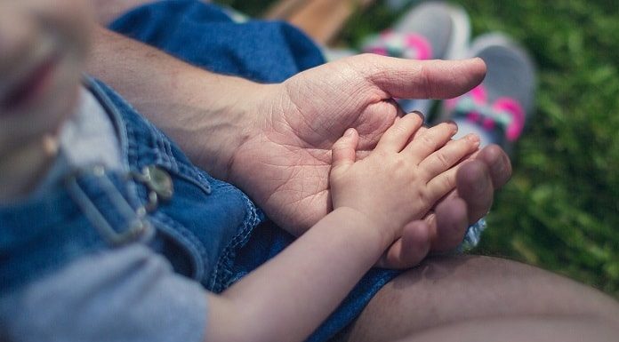 close em criança com a mãozinha sobre a mão de um homem adulto