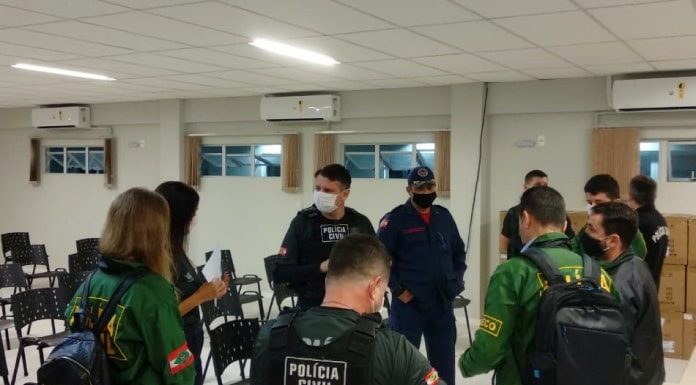 policiais homens e mulheres reunidos em pé em auditório usando uniformes da pc antes do início da operação