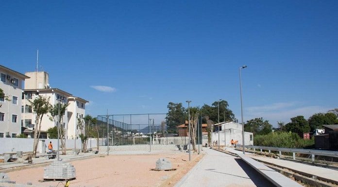 lajotas do piso colocadas em grande parte da área do parque e em outra chão de areia. prédios ao fundo